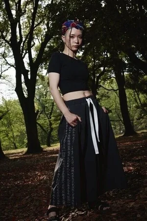 黒のクロップドTシャツに、文字柄の布を切り替えた黒のロングスカートを合わせたコーディネート