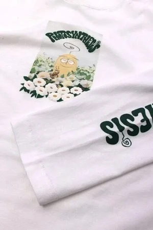 胸にキャラクターと花のイラスト、袖に文字をプリントした白いロングTシャツ
